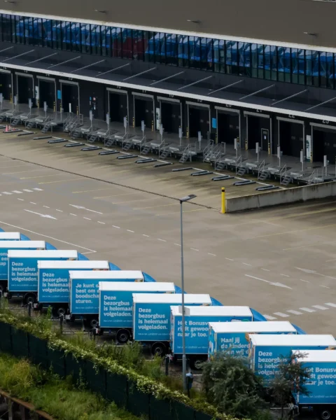 Albert Heijn-bezorgwagens staan geparkeerd bij een distributiecentrum met laadperrons.