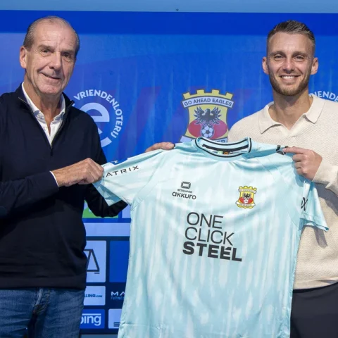 Jasper Cillessen poseert met een Go Ahead Eagles-shirt naast een clubvertegenwoordiger.