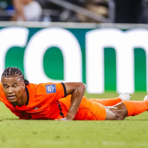 Nathan Aké ligt op het veld in een oranje voetbaltenue tijdens een wedstrijd.