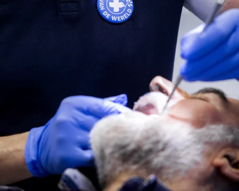 Tandartsbehandeling met handschoenen en mondspiegel bij een patiënt.