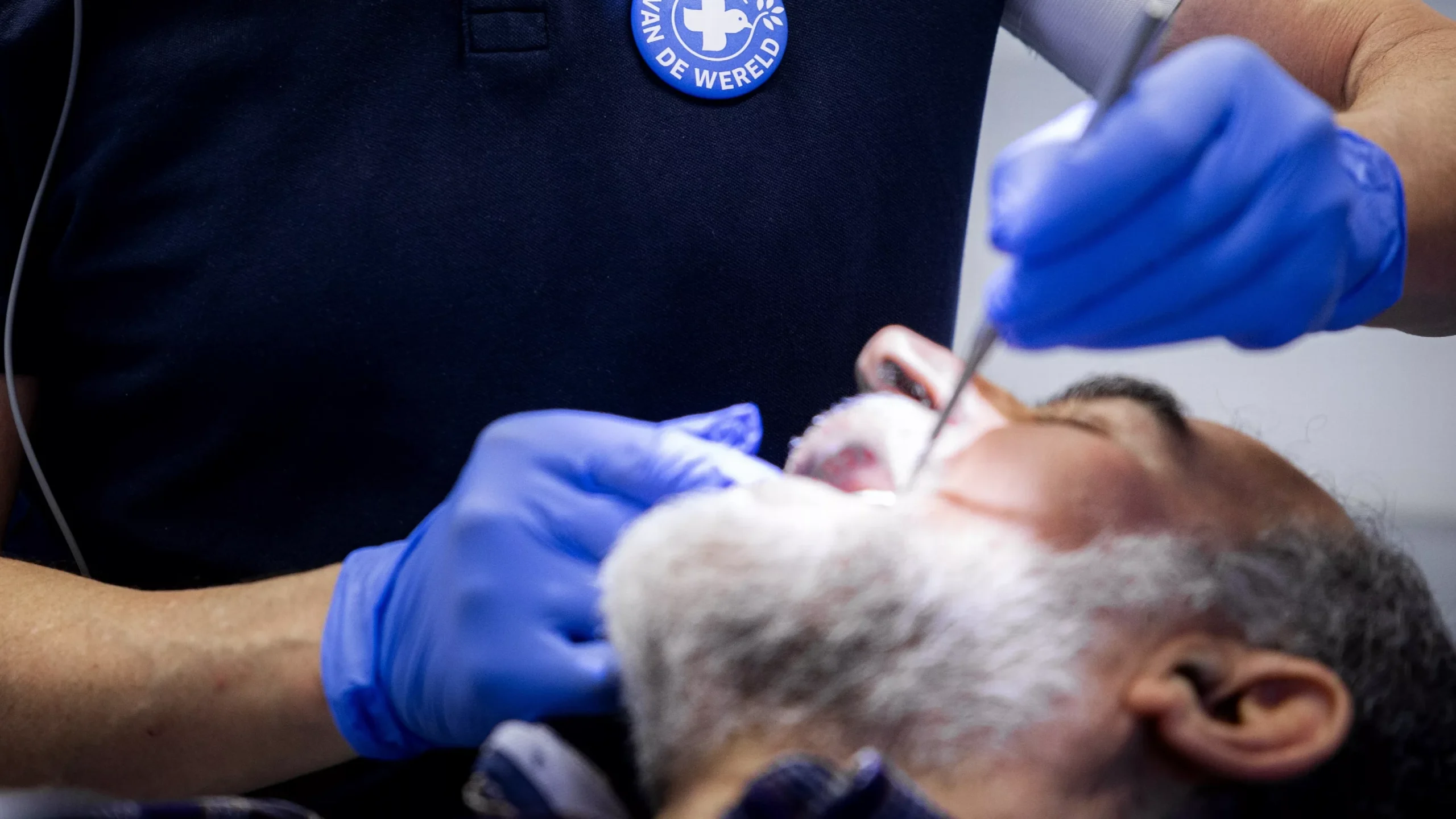 Tandartsbehandeling met handschoenen en mondspiegel bij een patiënt.