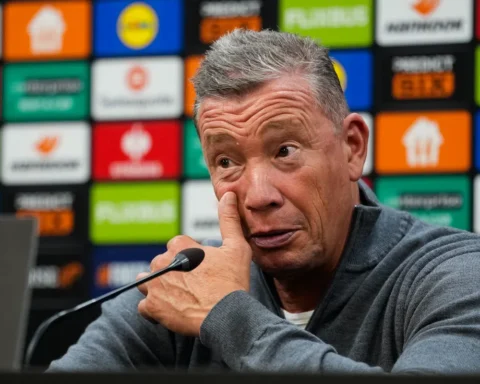 Leeroy Echteld spreekt op een persconferentie voor een sponsorachtergrond.