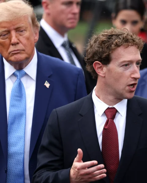 Mark Zuckerberg spreekt terwijl Donald Trump op de achtergrond staat, omringd door andere personen.