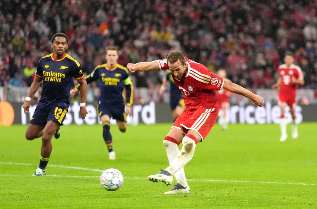 Bayern München-speler schiet op doel terwijl Arsenal-verdedigers toekijken.