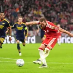 Bayern München-speler schiet op doel terwijl Arsenal-verdedigers toekijken.