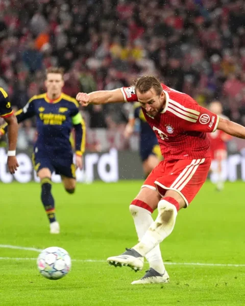 Bayern München-speler schiet op doel terwijl Arsenal-verdedigers toekijken.