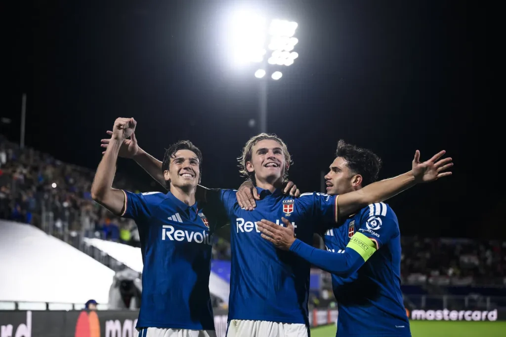 Spelers van Como vieren een doelpunt onder de stadionverlichting.