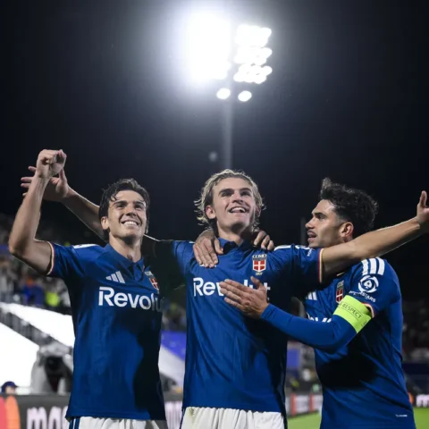 Spelers van Como vieren een doelpunt onder de stadionverlichting.