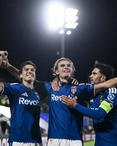 Spelers van Como vieren een doelpunt onder de stadionverlichting.